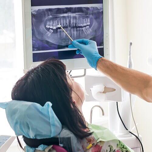 A dentist pointing out areas of interest in a patient's x-rays