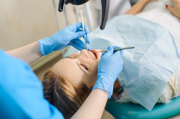 A female patient reclined in a dental chair undergoing periodontal therapy