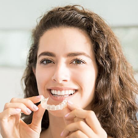 A patient holding her Candid clear aligners